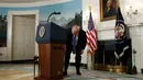 Presiden AS, Donald Trump mencari botol air minum dekat podium disela pidatonya di Ruang Diplomatik, Gedung Putih, Rabu (15/11). Di tengah pemaparan, Trump tiba-tiba terlihat seperti tenggorokannya terganggu dan diduga mengalami dahaga. (AP/Evan Vucci)