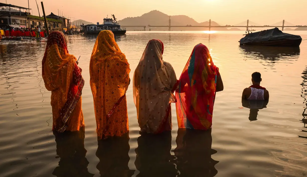 Umat Hindu memanjatkan doa kepada Dewa Matahari pada perayaan 'Chhath Puja' di tepi Sungai Brahmaputra di Guwahati pada Senin 27 Oktober 2025. (Biju BORO/AFP)