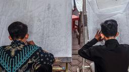 Pembuat batik menggambar pola pada kain saat proses pembuatan di Sidoarjo, Jawa Timur, Sabtu (1/10/2022). Indonesia akan memperingati Hari Batik Nasional pada 2 Oktober. (JUNI KRISWANTO/AFP)