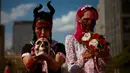 Dua orang perempuan mengenakan kostum dan dandanan menyerupai zombie selama acara Zombie Walk di Sao Paulo, Brasil, Sabtu (2/11/2019). Ratusan orang turun ke jalan memakai kostum karakter horor pada acara tahunan yang digelar sejak 2006 pada Hari Para Arwah. (Miguel SCHINCARIOL / AFP)