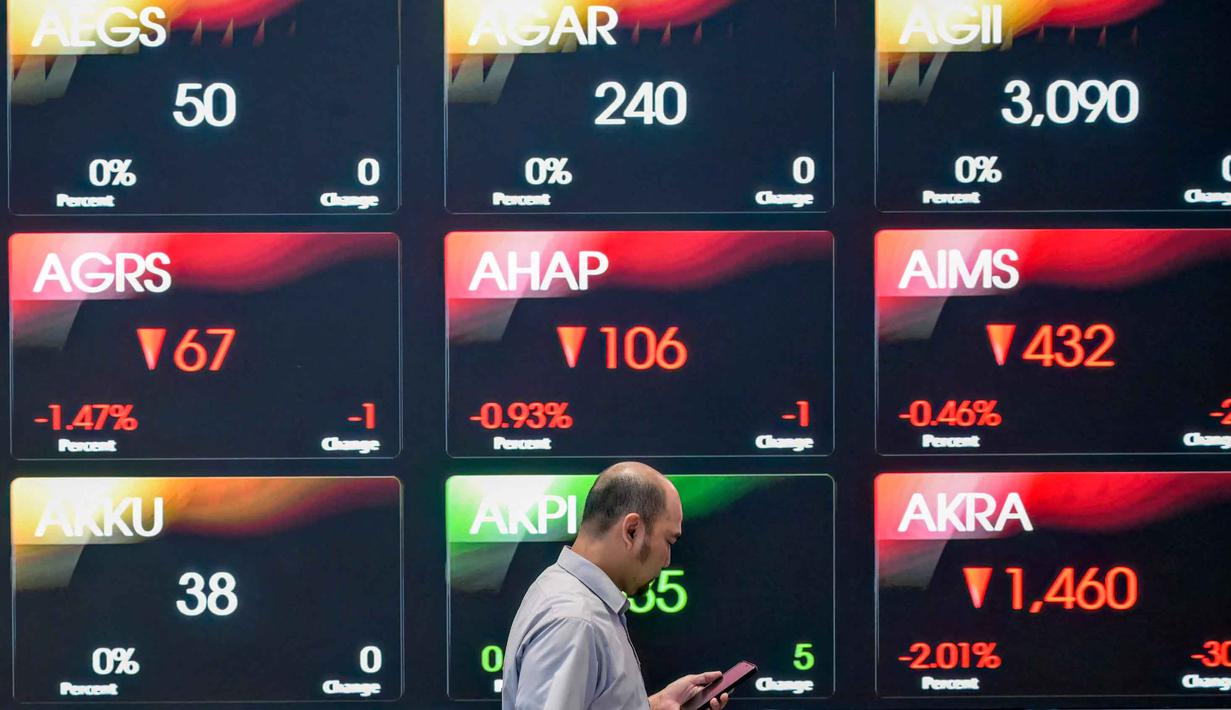 Seorang pria melihat ponselnya di depan layar yang menampilkan Indeks Harga Saham Gabungan (IHSG), yang anjlok signifikan selama pembukaan pasar, di gedung Bursa Efek Indonesia di Jakarta pada Rabu 13 Mei 2026. (BAY ISMOYO/AFP)