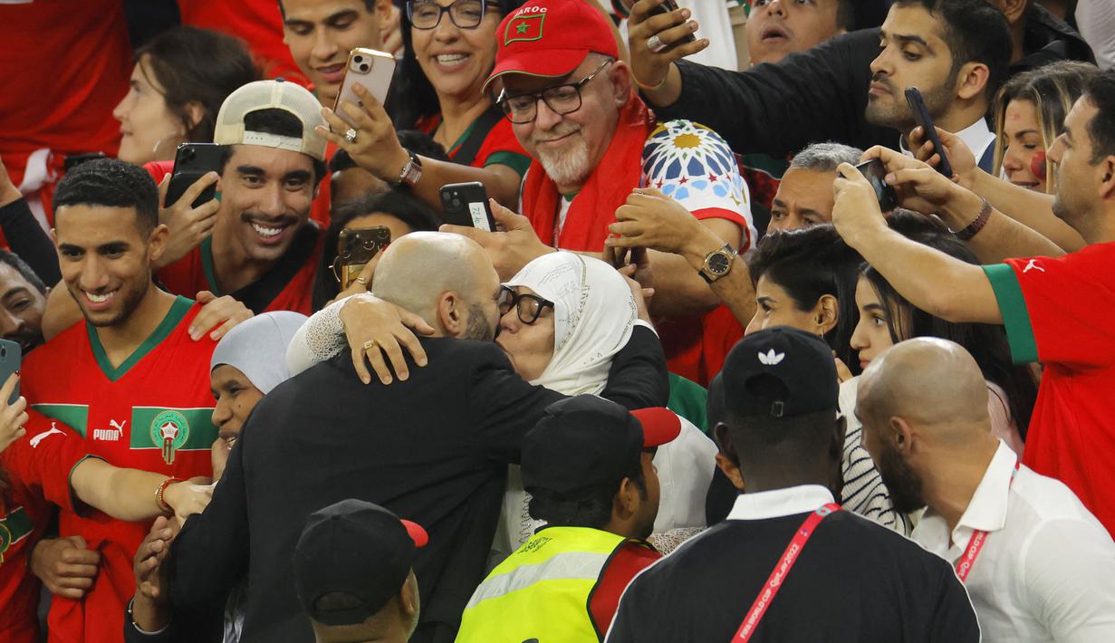 Pelatih Maroko, Walid Regragui, merayakan kemenangan atas Portugal bersama keluarganya pada laga perempat final di Stadion Al-Thumama, Sabtu (10/12/2022). (AFP/Odd Andersen)