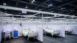 Petugas keamanan (kiri) berjaga di samping deretan kamar yang dipartisi di fasilitas perawatan kesehatan masyarakat di AsiaWorld-Expo di Hong Kong, Selasa (24/11/2020). Rumah sakit darurat khusus corona itu kembali dibuka menyusul lonjakan kasus COVID-19 di Hong Kong. (Anthony WALLACE/AFP)