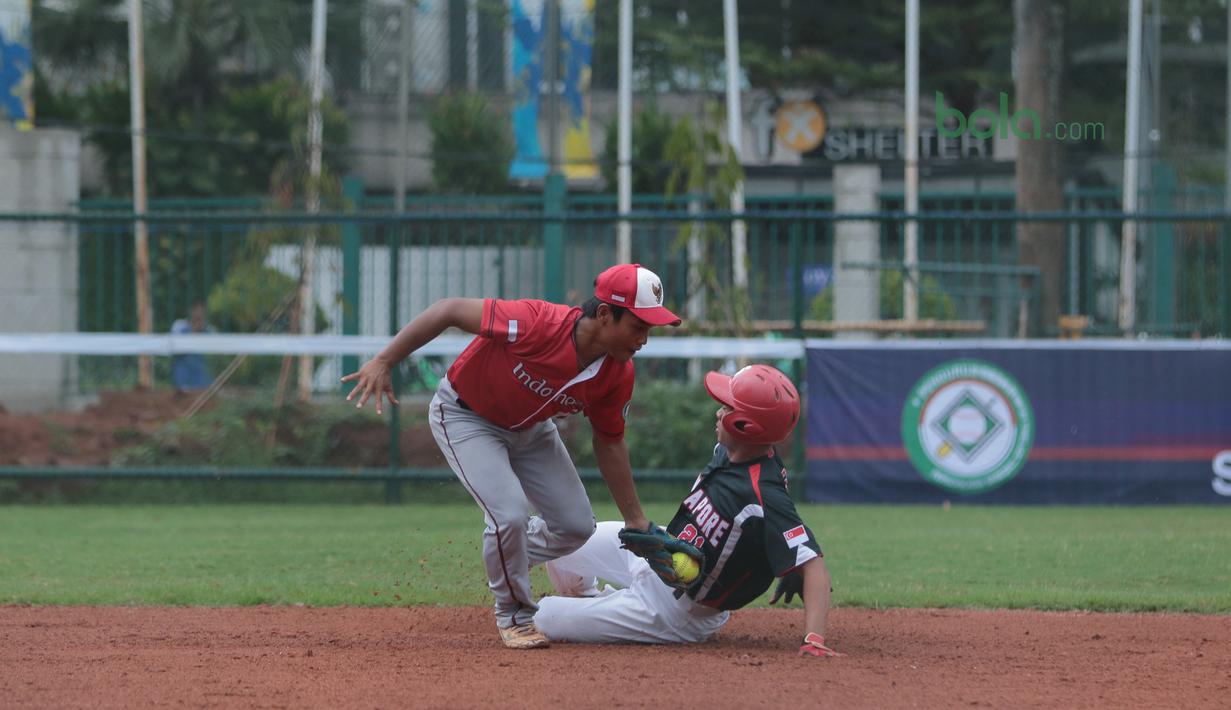 Pemain Indonesia, Hermansyah (kiri) mencoba mematikan langkah pemain Singapura pada laga Asian Softball Championship di Senayan, Jakarta,Selasa (25/4/2018). Indonesia menang atas Singapura 8-2. (Bola.com/Nick Hanoatubun)