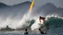 Peselancar menaiki ombak di Pantai Lhoknga, Kabupaten Aceh Besar, Provinsi Aceh, Indonesia, 20 Februari 2023. Karena pesonanya, banyak wisatawan lokal maupun mancanegara selalu ingin berkunjung kembali untuk menikmati segala keindahan pantai ini. (CHAIDEER MAHYUDDIN/AFP)
