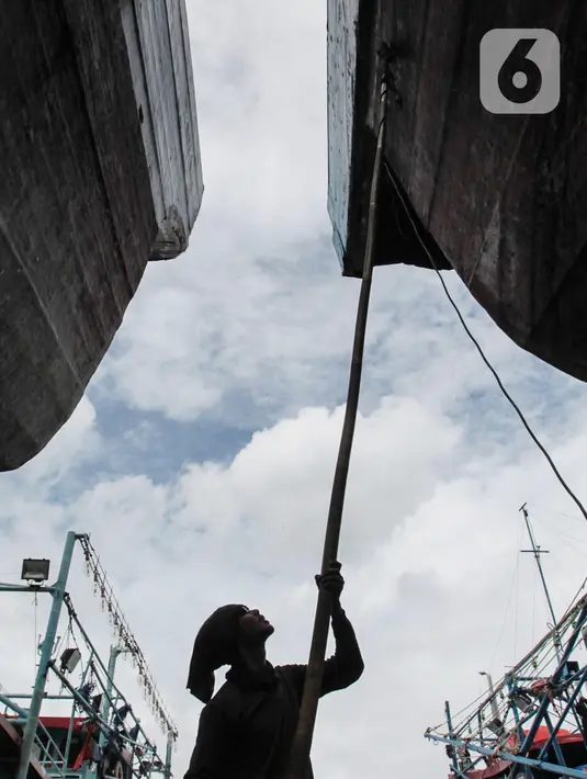 Buruh melakukan perbaikan kapal nelayan di Galangan kapal, Muara Angke, Jakarta, Minggu (23/12/2020). Bengkel kapal tersebut menjadi tumpuan pendapatan para pengusaha kapal barang dan ikan. (Liputan6.com/Angga Yuniar)