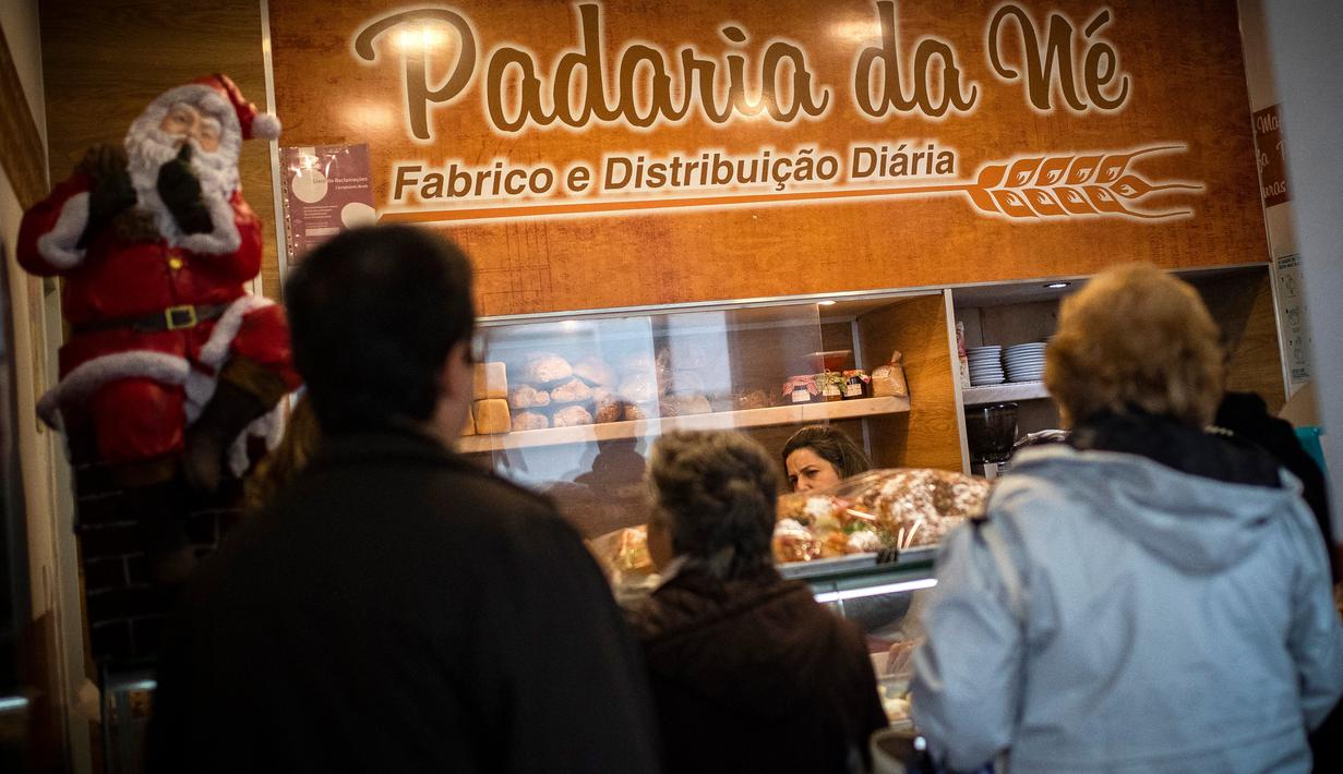 Pelanggan mengantre untuk membeli Bolo Rei atau Kue Raja di toko roti Padaria da Ne, Amadora, Portugal, 16 Desember 2022. Saat merayakan Natal, orang Portugal hampir tidak pernah melewatkan Bolo Rei dari sajian mereka. (CARLOS COSTA/AFP)