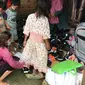 Fasilitator pendidikan KKI Warsi Yohana Marpaung (jaket ungu) sedang memasangkan sepatu untuk anak perempuan orang rimba. (Liputan6.com / dok KKI Warsi)