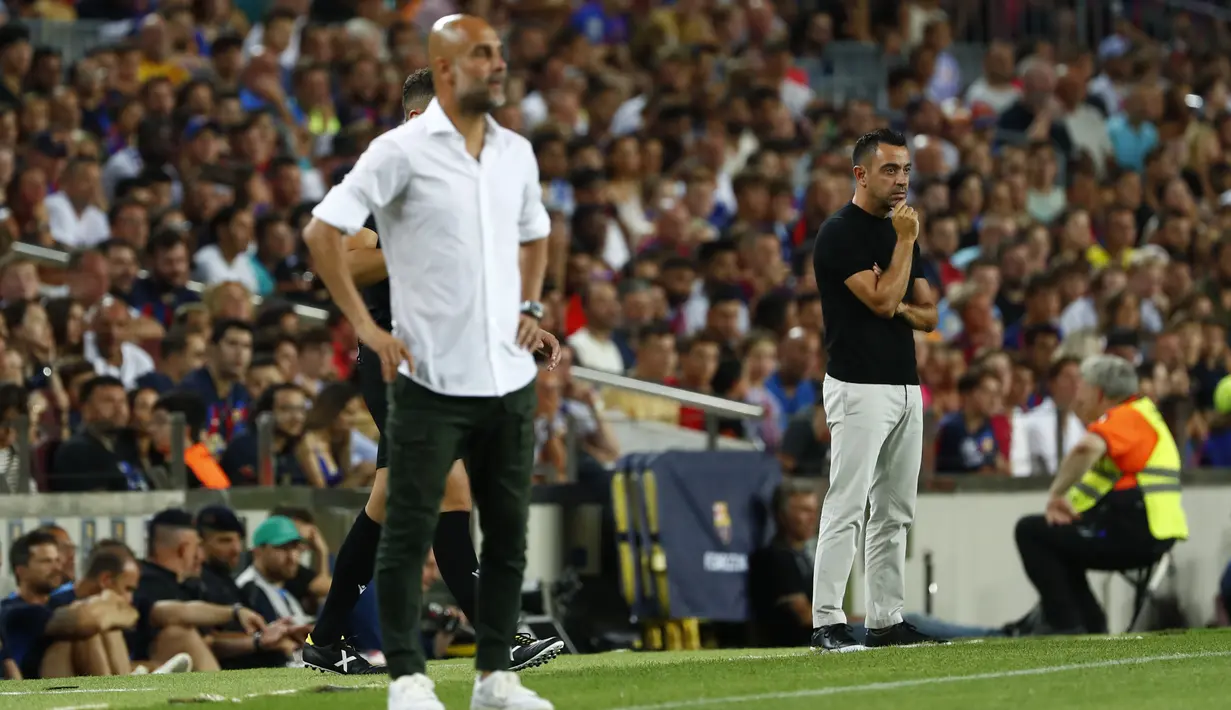 Manajer Manchester City, Pep Guardiola  dan pelatih Barcelona Xavi Hernandez berdiri di garis samping saat sebuah laga amal di Stadion Camp Nou, Kamis (25/8/2022) dinihari WIB. Laga ini berlangsung menarik karena mempertemukan sang guru dan murid yaitu Pep Guardiola selaku pelatih Man City dan Xavi Hernandes pelatih Barcelona. (AP Photo/Joan Monfort)
