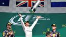 Pebalap Mercedes, Lewis Hamilton, melempar trofi juara F1 GP Jerman di Sirkuit Hockenheim, (31/7/2016). Dua pebalap Red Bull, Daniel Ricciardo dan Max Verstappen, finis kedua dan ketiga. (AFP/Thomas Kienzle)
