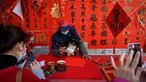 Seorang kaligrafer menulis kuplet musim semi, semacam dekorasi Tahun Baru Imlek, jelang dimulainya Tahun Baru Imlek di sebuah kios di Foshan, Provinsi Guangdong, China, 18 Januari. Kuplet adalah karya kaligrafi ala China dengan tinta hitam di atas kertas merah yang terdiri dari dua bait harapan atau pernyataan baik untuk menyambut Imlek. (Giok Gao/AFP)