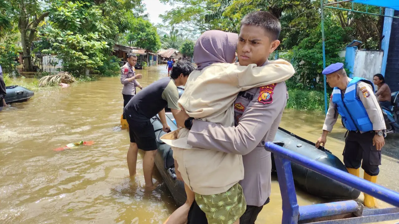 Personel Direktorat Polisi Air dan Udara Polda Riau menggendong wanita lansia yang menjadi korban banjir di Pekanbaru.