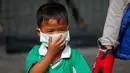 Seorang anak laki-laki mengenakan masker saat dijemput orang tuanya di Bangkok, Thailand (30/1).  Thailand sedang menghadapi persoalan polusi udara terburuk yang pernah terjadi di negera tersebut. (AP Photo/Sakchai Lalit)