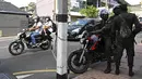 Para komuter melewati tentara yang berjaga di sepanjang jalan di Kolombo pada Sabtu (2/4/2022). Pasukan yang dipersenjatai dengan senapan serbu otomatis dikerahkan di Sri Lanka untuk mengendalikan massa, beberapa jam setelah presiden menyatakan keadaan darurat. (KODIKARA / AFP)