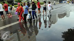 Warga memadati Jalan M.H. Thamrin saat kegiatan Car Free Day di Jakarta, Minggu (24/1/2016). Meski hujan mengguyur Ibu Kota sejak semalam, kegiatan CFD pagi di kawasan Bundaran Hotel Indonesia masih tetap ramai. (Liputan6.com/Helmi Affandi)