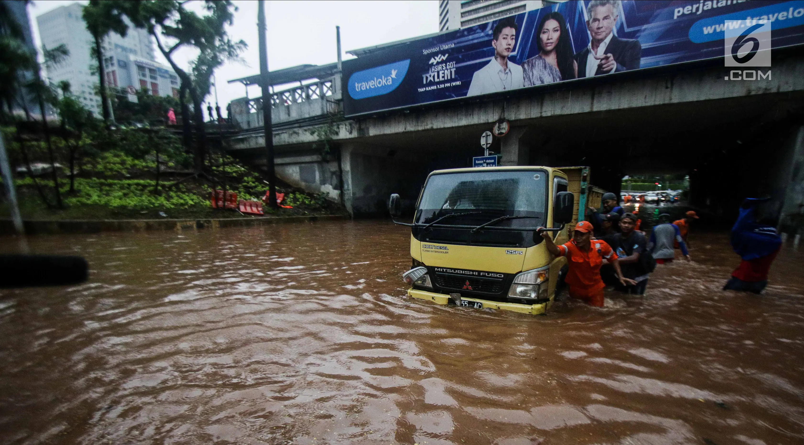 Petugas dibantu warga mendorong truk yang mogok akibat terjebak banjir di terowongan Dukuh Atas, Jakarta, Senin (11/12). Hujan lebat yang mengguyur ibu kota mengakibatkan genangan hingga satu meter di lokasi tersebut. (Liputan6.com/Faizal Fanani)