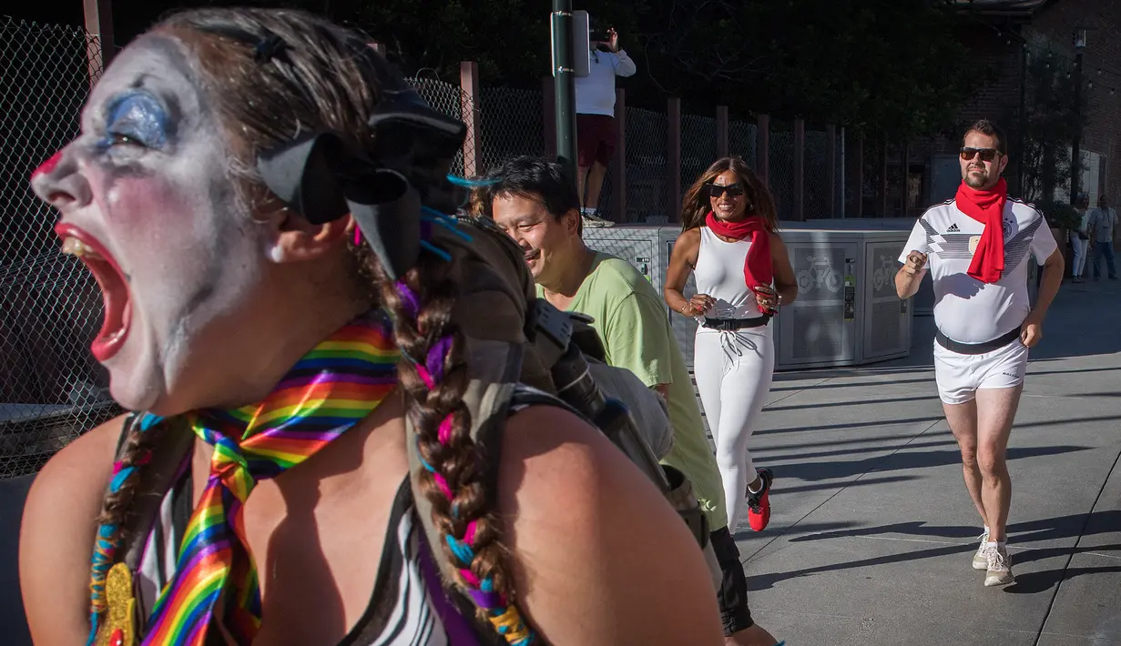Peserta berdandan seperti badut berlarian selama acara parodi tahunan "Running of the Clowns" di Pasadena, California pada 20 Oktober 2019. Lari dikejar kawanan badut ini merupakan parodi yang mengolok-olok lomba dikejar banteng di Spanyol. (Mark RALSTON / AFP)