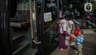 Seorang warga bersama anaknya bersiap menaiki bus tujuan mereka untuk mudik bareng gratis BUMN di kawasan Jakarta, Rabu (27/4/2022). Program mudik gratis merupakan salah satu solusi untuk mengantisipasi potensi kepadatan lalu lintas pada masa Lebaran.(Liputan6.com/Faizal Fanani)