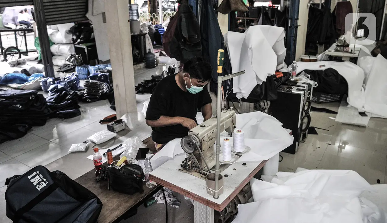Pekerja menyelesaikan pembuatan baju hazmat di salah satu industri konveksi Pusat Industri Kecil (PIK), Jakarta, Rabu (30/12/2020). Selain pesanan langsung, baju hazmat kini laris dijual melalui online shop. (merdeka.com/Iqbal S. Nugroho)