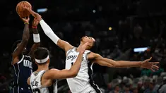 Pebasket San Antonio Spurs, Victor Wembanyama (kanan) berusaha merebut bola dari pebasket Dallas Mavericks pada laga pertama NBA musim 2023/2024 di AT&T Center in San Antonio, Texas, Kamis (27/10/2023). Ini merupakan laga perdana bagi Wembanyama di NBA. (AFP/Chandan Khanna)