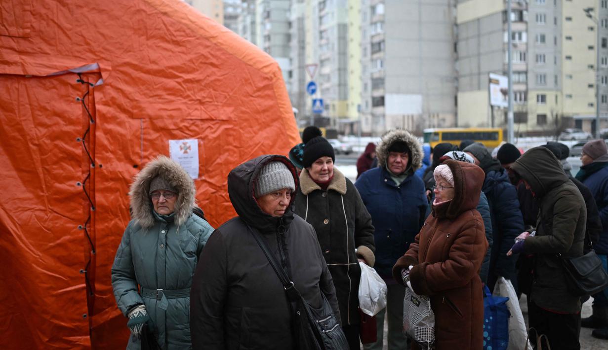 Gangguan pada infrastruktur energi akibat konflik berkepanjangan membuat banyak warga kehilangan akses untuk memasak di rumah. Tampak dalam foto, warga setempat berkumpul untuk menerima makanan hangat yang dibagikan oleh sukarelawan dari badan amal makanan yang berbasis di Amerika Serikat (AS), World Central Kitchen, membagikan makanan hangat kepada warga setempat di sebuah kawasan perumahan di Kyiv yang mengalami pemadaman listrik dan air akibat serangan Rusia yang menghantam sektor energi, Kamis 22 Januari 2026. (Sergei GAPON/AFP)