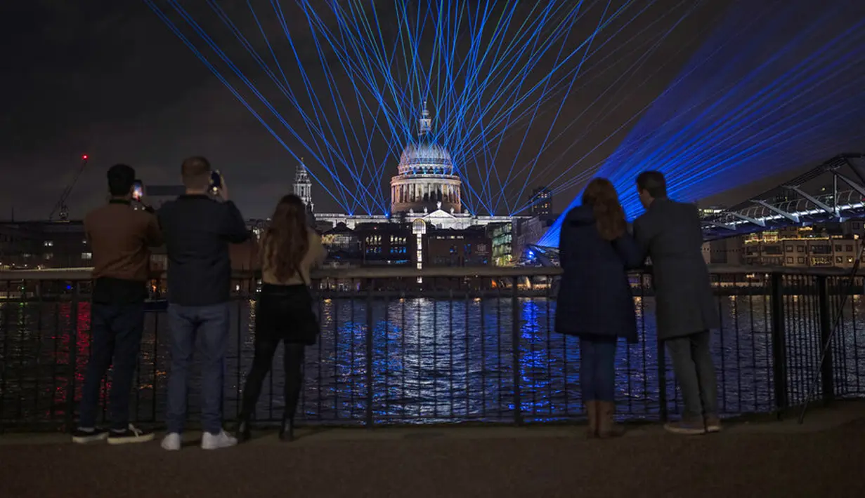 Lampu dan laser ditampilkan untuk menandai awal tahun 2022 setelah tengah malam di Jembatan Milenium yang melintasi Sungai Thames dan kubah Katedral St Paul di London, Inggris, Sabtu (1/1/2022). Pesta kembang api ditiadakan untuk tahun kedua berturut-turut karena COVID-19. (AP Photo/Matt Dunham)