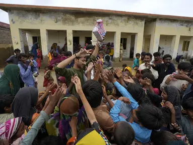 Seorang sukarelawan membagikan makanan kepada anak-anak di sebuah kamp yang didirikan di gedung sekolah untuk para pengungsi internal dari daerah pesisir saat Topan Biparjoy mendekat di Badin, Provinsi Sindh, Pakistan, Kamis (15/6/2023). India dan Pakistan yang menderita banjir mematikan tahun lalu bersiap untuk banjir baru saat Topan Biparjoy mendekat dengan cepat. (AP Photo/Fareed Khan)