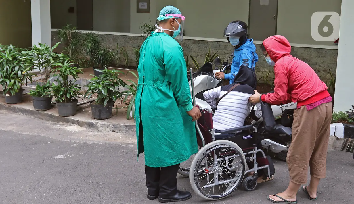 Petugas medis (kiri) mendorong pasien yang duduk di kursi roda di IGD RSUD Cengkareng, Jakarta, Rabu (23/6/2021). Meningkatnya kasus COVID-19 di Jakarta membuat pasien harus mengantre di luar IGD untuk mendapatkan tempat perawatan. (Liputan6.com/Herman Zakharia)