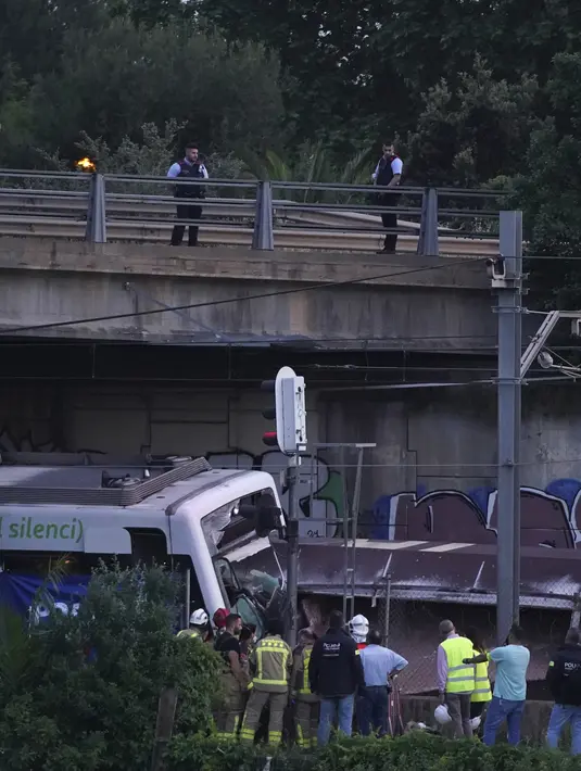 Polisi dan petugas penyelamat berdiri di dekat reruntuhan setelah kecelakaan kereta api di Sant Boi dekat Barcelona, Spanyol, Senin, 16 Mei 2022. Sebuah kereta barang menabrak kereta penumpang pada jam sibuk di Catalonia, menewaskan seorang insinyur dan melukai 85 orang saat itu. (AP Photo/Joan Mateu Para)