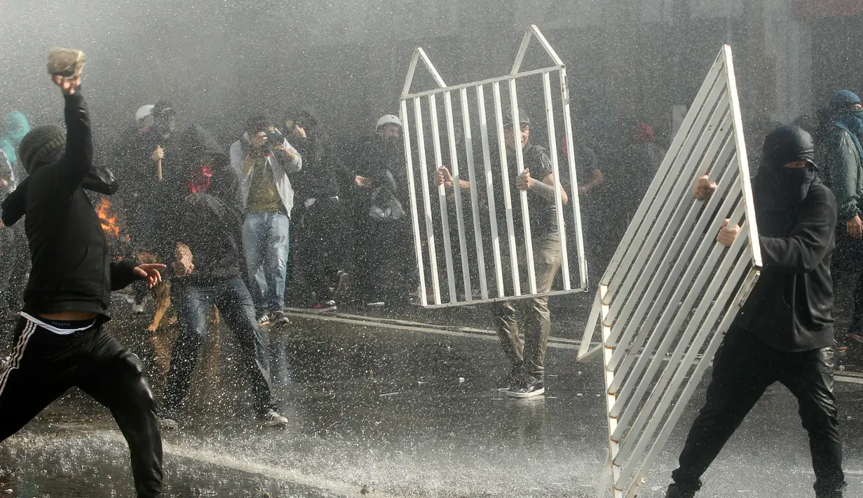 Demonstran merusak pagar saat terjadi bentrok dengan polisi di sekitar Kongres di Valparaiso, Chili. Sabtu (21/5). Peristiwa itu menyebabkan sejumlah gedung terbakar dan seorang polisi tewas. (AFP Photo/Claudio Reyes)