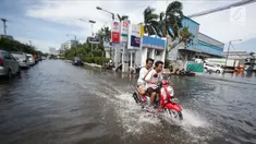 Dua orang remaja mengendarai motor melintasi banjir rob di kawasan Muara Baru, Jakarta, Rabu (6/11). Banjir Rob akibat laut pasang ini, membuat sejumlah aktivitas warga terganggu. Termasuk aktivitas di pasar ikan terhenti. (Liputan6.com/Faizal Fanani)