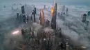 Secara umum, di Kuwait, kabut tebal lebih sering muncul selama musim dingin (Desember hingga Maret) karena suhu malam hari yang lebih rendah dan kelembapan yang lebih tinggi. Tampak foto udara memperlihatkan gedung pencakar langit yang tertutup kabut pagi di Kota Kuwait pada Minggu 9 November 2025. (YASSER AL-ZAYYAT/AFP)