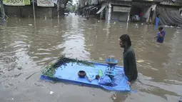 Seorang pedagang mendorong gerobaknya melintasi jalan yang banjir setelah hujan deras di Lahore, Pakistan (16/7/2019). Banjir bandang merusak lebih dari 120 rumah, 30 toko dan melumpuhkan pasokan air dan listrik. (AP Photo/K.M. Chaudary)