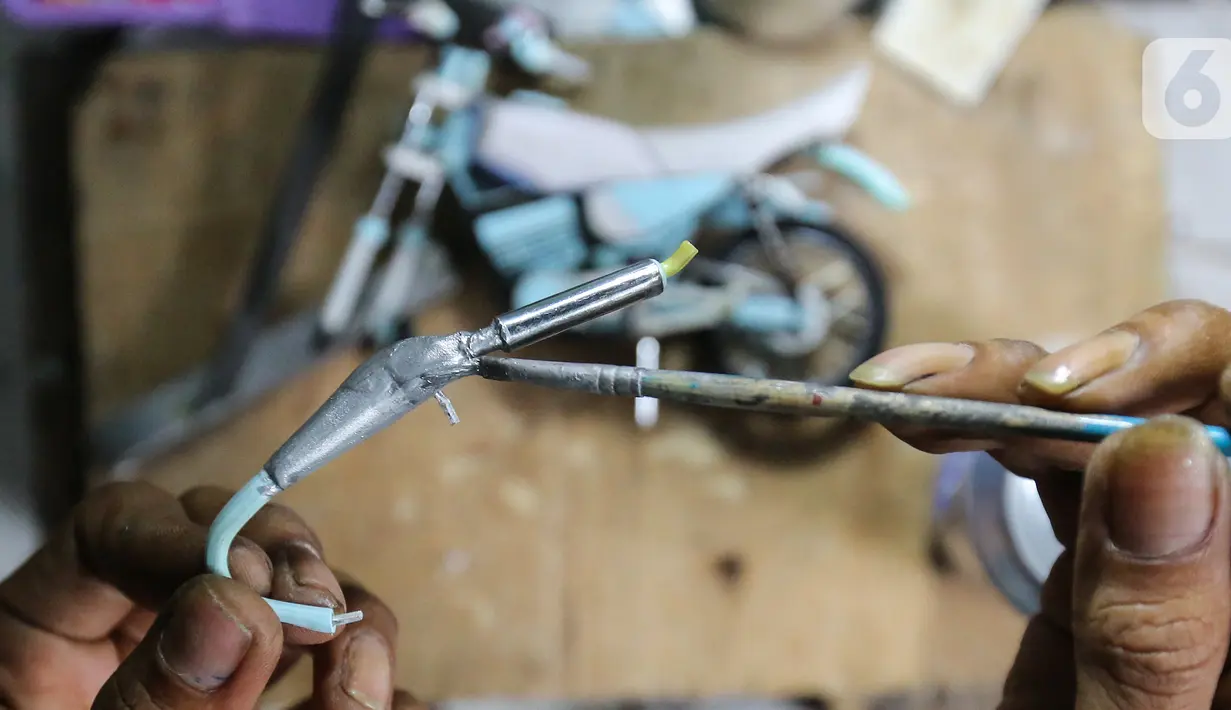 Pengrajin Wawang Kurniawan, mengecat knalpot miniatur motor RX-King di Kampung Dukuh, Serua, Tangerang Selatan, Sabtu (17/10/2020). Miniatur motor dengan rasio 1:18 yang dikerjakan sendiri mampu memproduksi 1 buah dalam jangka waktu dua hari. (Liputan6.com/Fery Pradolo)
