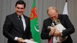 Presiden Rusia, Vladimir Putin (kanan) memncium anjing gembala Turkmen atau dikenal sebagai Alabai pemberian Presiden Turkmenistan Gurbanguly Berdimuhamedov saat pertemuan di Sochi, Rusia (11/10). (AFP Photo/Pool/Maxim Shemetov)