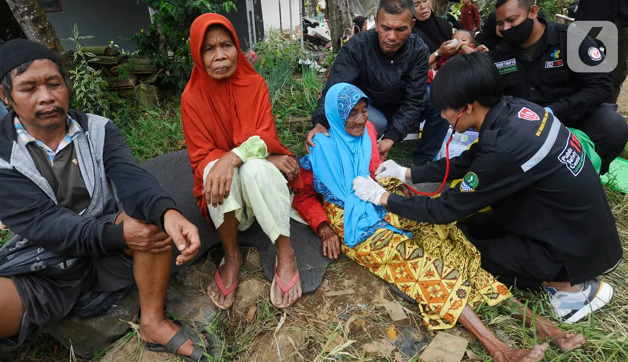 Tenaga medis dari Dinas Kesehatan Kabupaten Karawang melakukan pemeriksaan kesehatan seorang lansia pengungsi korban gempa bumi di desa Mangunkerta, kecamatan Cugenang, Cianjur, Jawa Barat, Rabu (23/11/2022). Hari ketiga pasca gempa magnitudo 5,6 mengguncang Cianjur, Kementerian Kesehatan (Kemenkes) mengirimkan sejumlah dokter termasuk dokter spesialis dan kebutuhan obat-obatan. (merdeka.com/Arie Basuki)