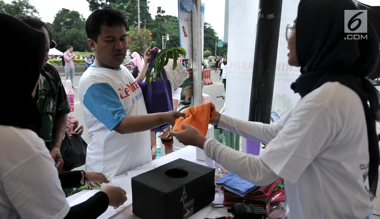 Warga menerima handuk setelah menukarkan tiga botol plastik bekas di stan ENVIRUN selama hari bebas kendaraan atau car free day (CFD) di Jakarta, Minggu (8/4). (Merdeka.com/Iqbal Nugroho)
