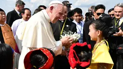 Paus Fransiskus menerima bunga saat disambut anak-anak di Bandara Internasional Yangon, Myanmar (27/11). Kedatangan Paus juga disambut dengan pakaian tradisional etnik, lambaian bendera dan tari-tarian di bandara Yangon. (AFP Photo/Vincenzo Pinto)