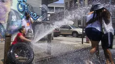 Jennifer Pagan (kiri) menyemprotkan air ke teman-temannya dari hidran kebakaran yang terbuka di bagian The Bronx, New York, Jumat (22/7/2022). Suhu tinggi yang berbahaya mengancam sebagian besar Timur Laut dan Selatan Jauh saat jutaan orang Amerika mencari kenyamanan dari AC , hidran kebakaran, air mancur dan pusat pendinginan.  (AP Photo/Seth Wenig)