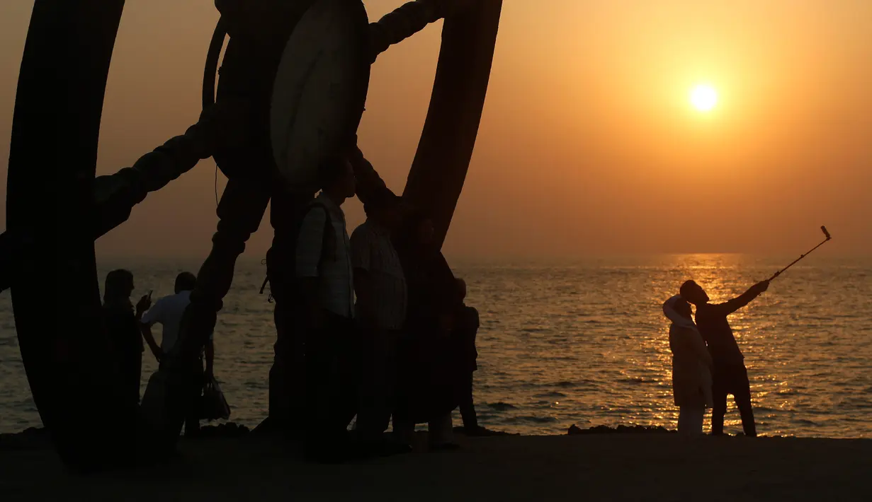 Turis mengabadikan gambar saat matahari tenggelam atau sunset di pinggir laut, Pulau Kish, Iran, 1 November 2016. Kish sudah menarik 1,8 juta pengunjung per tahun, dari 2,2 juta pada 2009 menjadi 5,2 juta pada 2015. (Atta Kenare/AFP)