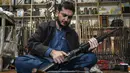 Seorang pedagang senjata Muhammad Jahanzeb memeriksa senjata otomatis di tokonya di Kota Darra Adamkhel, Pakistan, 4 Januari 2023. Pasar gelap senjata di Kota Darra Adamkhel dipenuhi dengan senapan Amerika palsu, replika revolver, dan AK-47 palsu. (Abdul MAJEED/AFP)