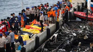 Petugas kepolisian bersama Tim SAR gabungan bersiap mengevakuasi kantong jenazah berisi penumpang kapal Zahro Express yang terbakar, di Pelabuhan Muara Angke, Minggu (1/1). Sedikitnya 23 orang tewas dan 17 lainnya masih hilang. (REUTERS/Darren Whiteside)