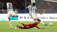 Pemain Timnas Indonesia, Marselino Ferdinan (tengah) terjatuh ketika berebut dengan pemain Argentina, Nahuel Molina (kiri) dan Cristian Romero pada laga FIFA Matchday di Stadion Utama Gelora Bung Karno (SUGBK), Senayan, Jakarta, Senin (19/06/2023). (Bola.com/Bagaskara Lazuardi)