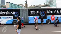 Sebuah bus TransJakarta koridor 1 dengan stiker bertuliskan Merdeka atau Macet melintas ketika masyarakat Jakarta tengah berolahraga saat Car Free Day (CFD) di kawasan Bundaran HI, Jakarta, (14/08). (Liputan6.com/Fery Pradolo).