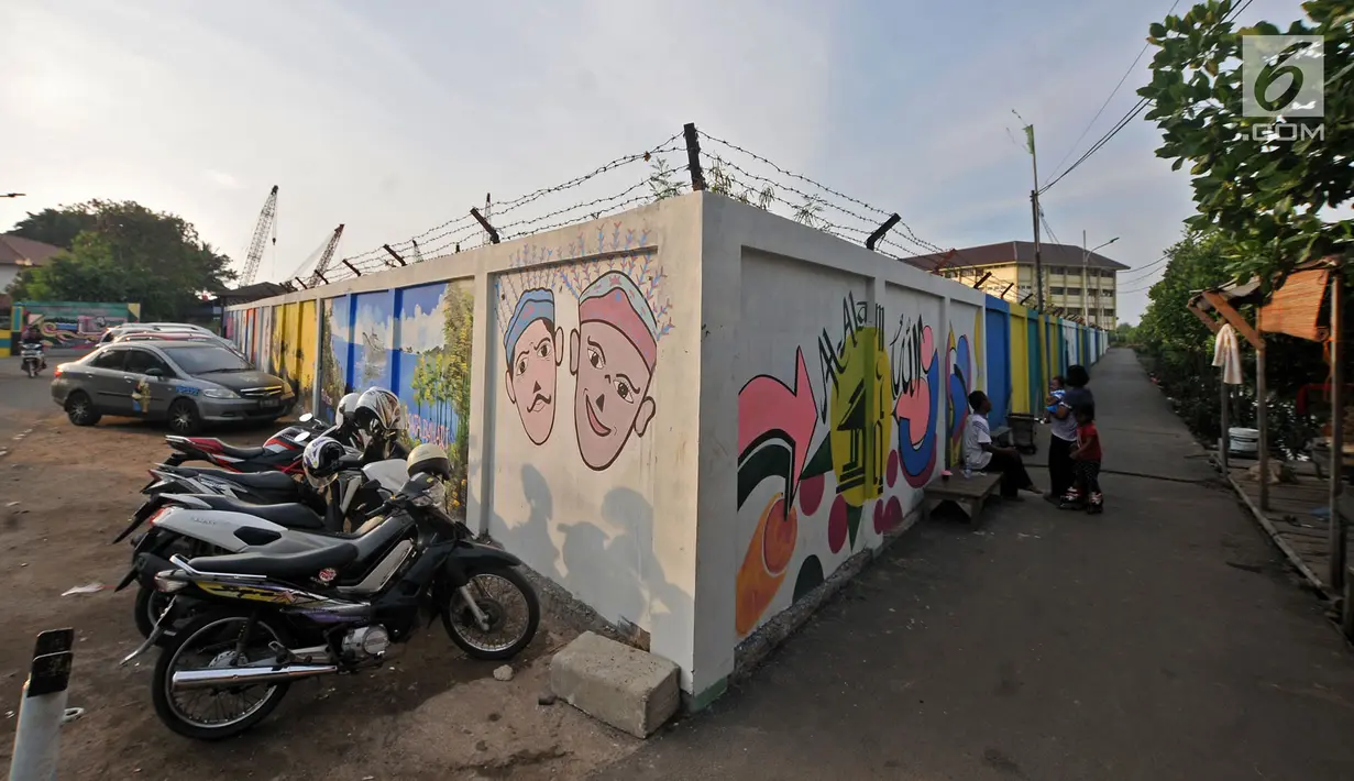 Aktivitas warga di dekat mural Betawi yang berada di Kampung Pitung, Marunda, Jakarta, Senin (2/7). Mural-mural bernuansa Betawi kini menghiasi destinasi wisata rumah dan masjid Pitung. (Merdeka.com/Iqbal S. Nugroho)