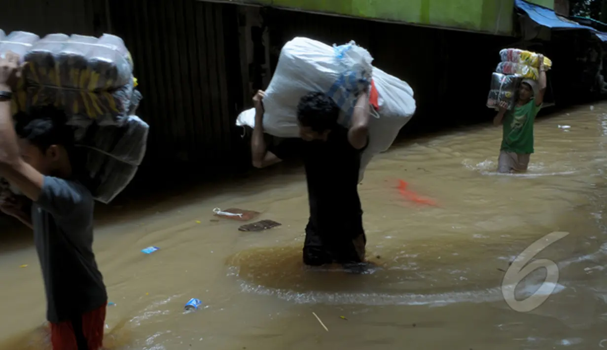 Intensitas curah hujan yang tinggi sejak Minggu (8/2) membuat Sungai Pesanggrahan meluap. Tampak sejumlah pedagang memindahkan barang dagangannya di Pasar Cipulir, Jakarta, Selasa (10/2/2015).(Liputan6.com/Andrian M Tunay)
