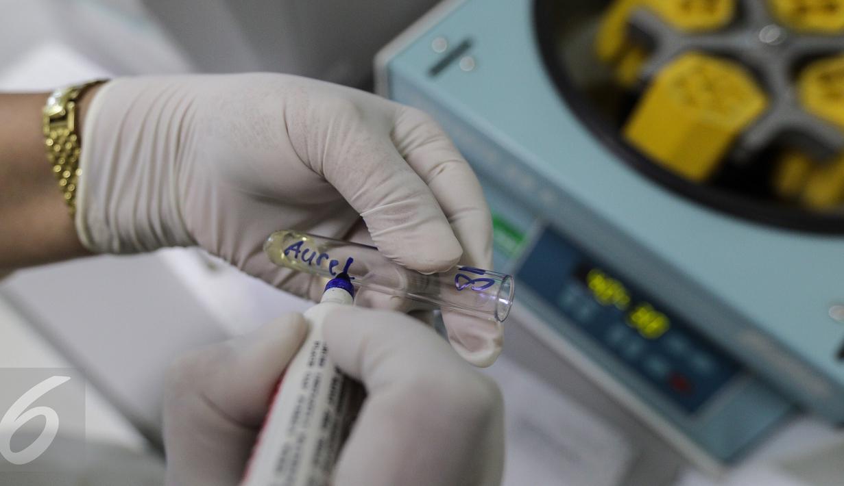 Teknisi kesehatan sedang menulis nama pasien di tabung pemutaran darah laboratorium kesehatan, Rumah Sakit Husada, Jakarta, Rabu (08/2). (Fery Pradolo/Liputan6.com)