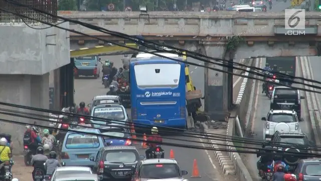 Bus Transjakarta tersangkut jembatan rel kereta api.