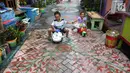 Anak-anak bermain sepeda dengan lantai warna-warni cat dinding dan grafiti di Kampung Bekelir, Babakan Kota Tangerang, Jumat (16/11). Sebanyak 120 seniman mural dilibatkan untuk mengecat rumah. (Liputan6.com/Fery Pradolo)