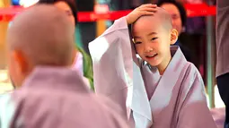 Reaksi seorang anak usai dicukur saat upacara 'Anak-anak Menjadi Buddha Monks', di kuil Jogye, Seoul, Rabu (19/4). Setelah upacara anak-anak akan tinggal di kuil selama dua minggu untuk mengikuti perayaan ulang tahun Buddha. (AFP PHOTO / JUNG Yeon-Je)